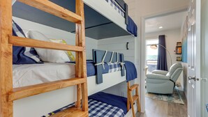 Habitación con literas, una escalera de madera, una silla y vistas al exterior.