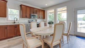 Una cocina moderna con armarios de madera, una isla central y un comedor con sillas.