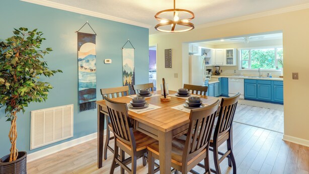 A dining area with a wooden table and chairs, a hanging light fixture, and a potted plant. - Black Mountain Retreat w/ Hot Tub + Mountain Views (Black Mountain)