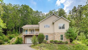 A two-story house with a front porch, a garage, and a stone facade. - Black Mountain Retreat w/ Hot Tub + Mountain Views (Black Mountain)