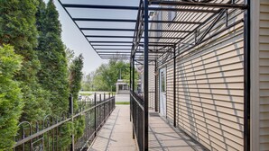 En överbyggd gångväg med metallräcken, en betonggång och en byggnad med beige fasadbeklädnad.