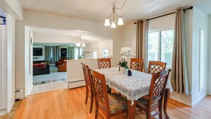 A dining area with a wooden table, lace tablecloth, and six wooden chairs. - 3 Mi to Pioneer Park & University: Spacious Home! (Fairbanks)