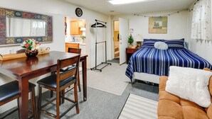 Une chambre à coucher avec un lit, un bureau et une chaise. Il y a une fenêtre avec des rideaux, une lampe et une horloge au mur.