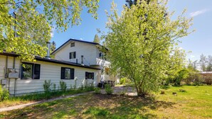 Une maison à deux étages avec un jardin devant, une cheminée et un petit espace jardin.