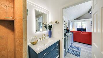 A bathroom with a marble sink, a mirror, and a vase with a plant.