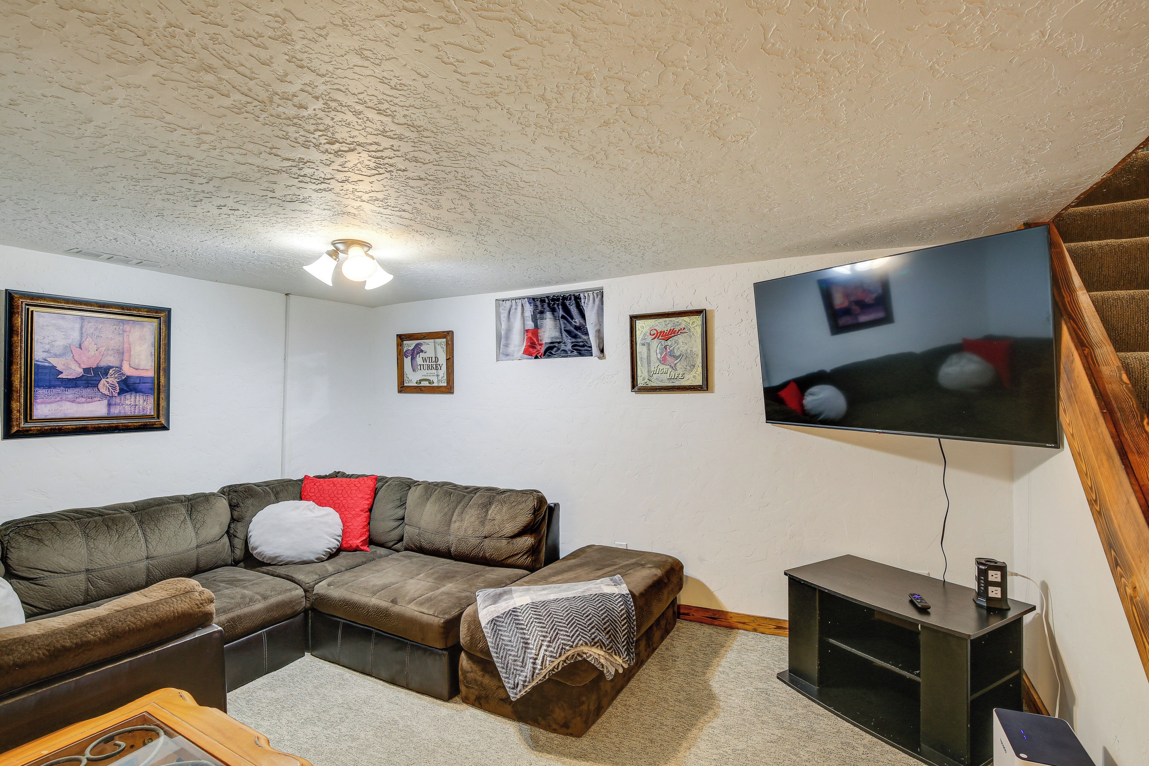 Een woonkamer met een hoekbank, een flatscreen televisie en een kleine houten tafel.