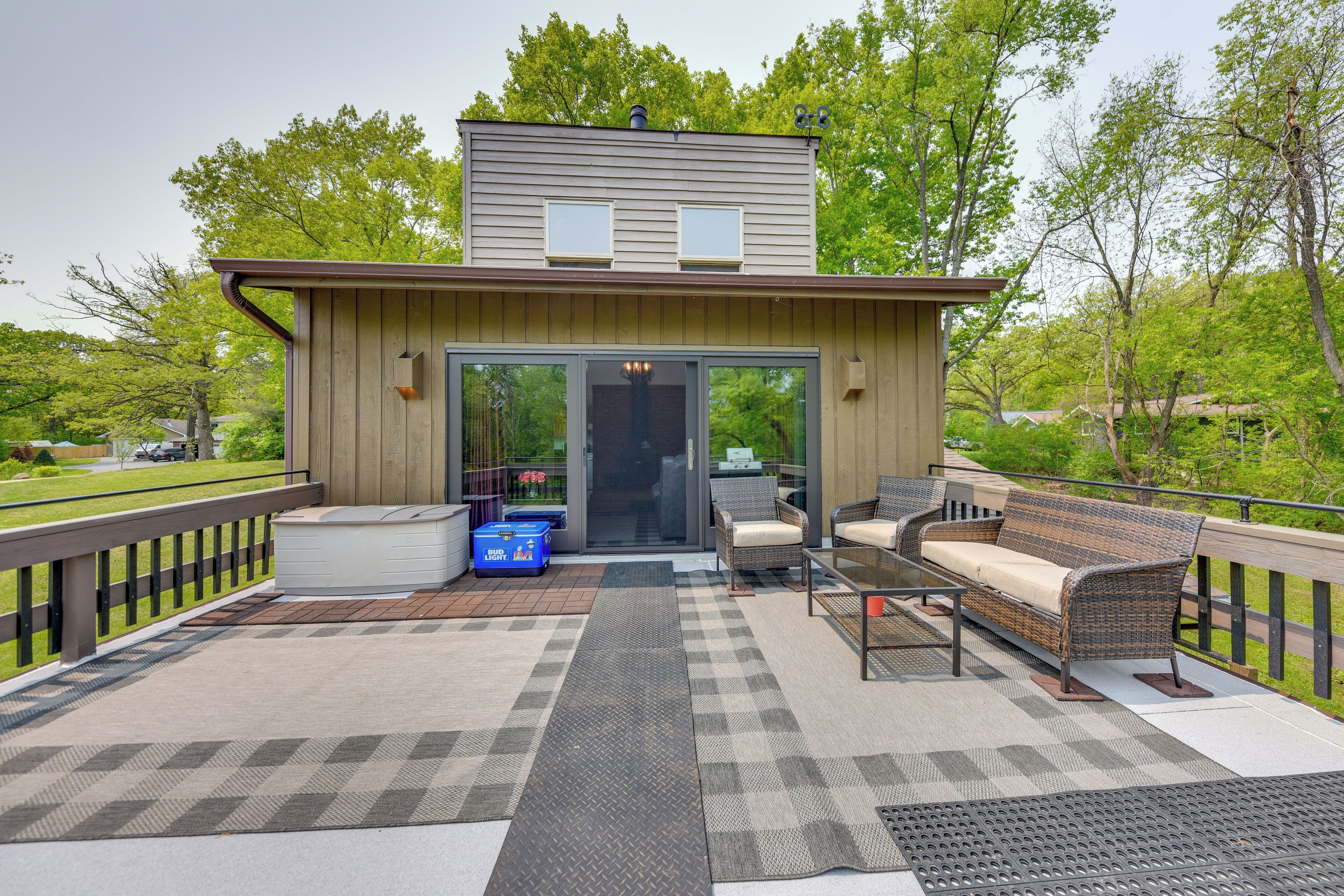A modern outdoor deck with a built-in seating area, a hot tub, and a glass door entrance.