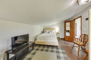 Un dormitorio con una cama, televisor, una silla de madera y una alfombra.