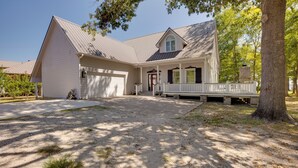 A two-story house with a front porch, garage, and a large tree in the foreground.