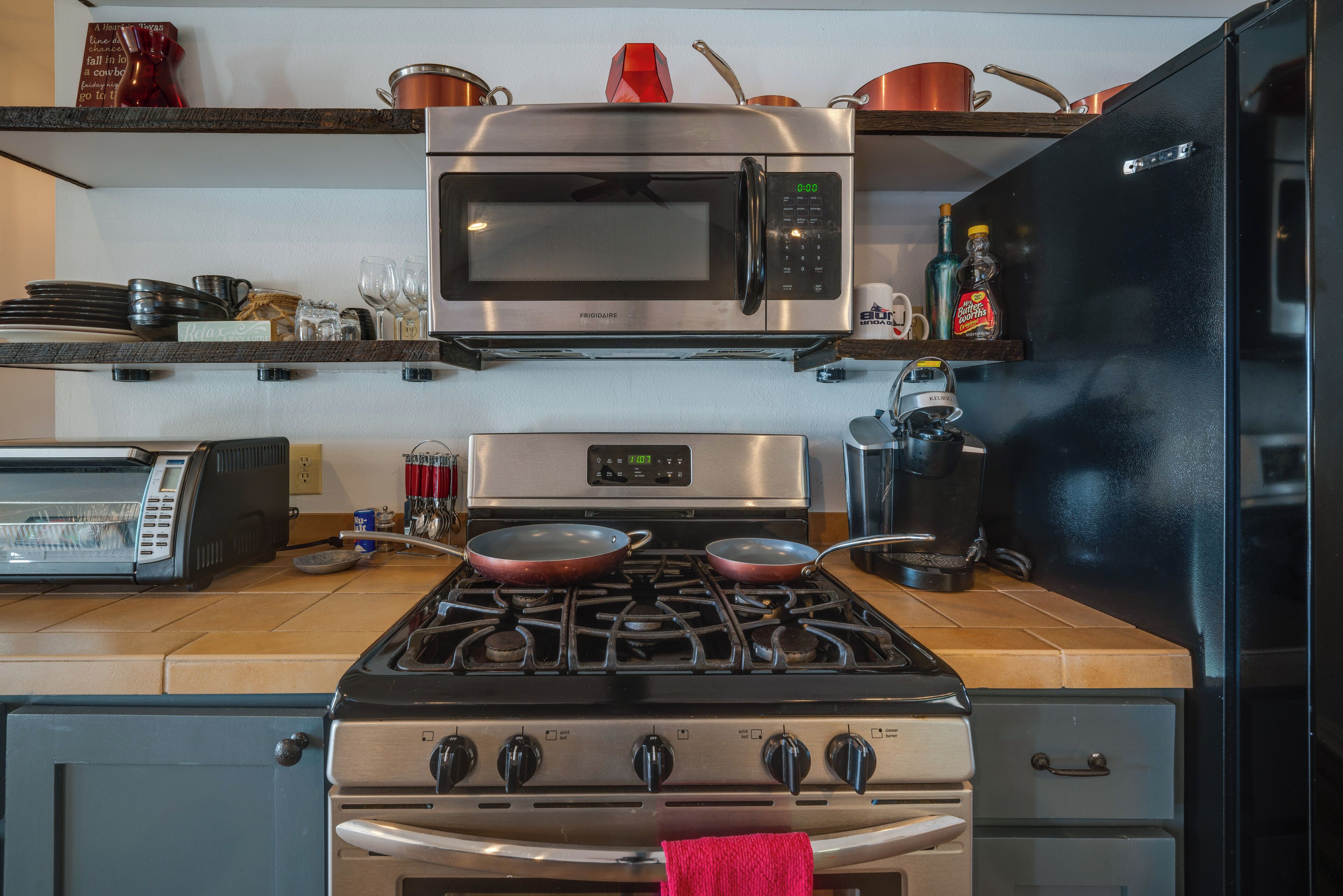 A kitchen with a stainless steel microwave, a gas stove, and a coffee maker.