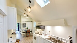 Una cocina moderna con armarios blancos, electrodomésticos de acero inoxidable y un tragaluz.