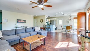 A spacious living room with a grey sectional sofa, a wooden coffee table, and a ceiling fan. - Waterfront Pass Christian Oasis ~ 2 Mi to Beach! (Pass Christian)