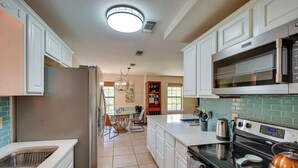 A kitchen with white cabinets, a stainless steel refrigerator, a black stove, and a microwave. - Waterfront Pass Christian Oasis ~ 2 Mi to Beach! (Pass Christian)