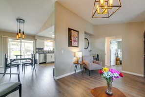 A spacious living area with a dining set, a side table with a lamp, a chair, and a vase of flowers. - Florida Vacation Rental w/ Enclosed Porch! (Beverly Hills)