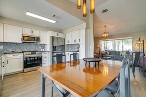 A modern kitchen with white cabinets, a wooden dining table, and a built-in oven. - Florida Vacation Rental w/ Enclosed Porch! (Beverly Hills)