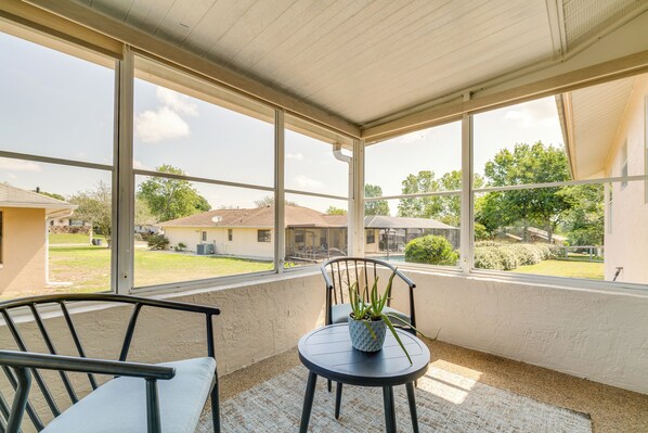 A covered patio with a table and chairs, a potted plant, and a view of a residential neighborhood. - Florida Vacation Rental w/ Enclosed Porch! (Beverly Hills)