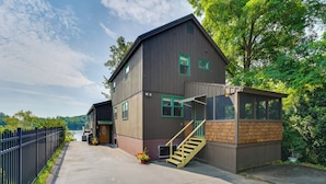 A two-story building with a wooden exterior, a staircase, and a view of a body of water. - Porch & Views: Queensbury 'three Family Lakehouse' (Lake George)