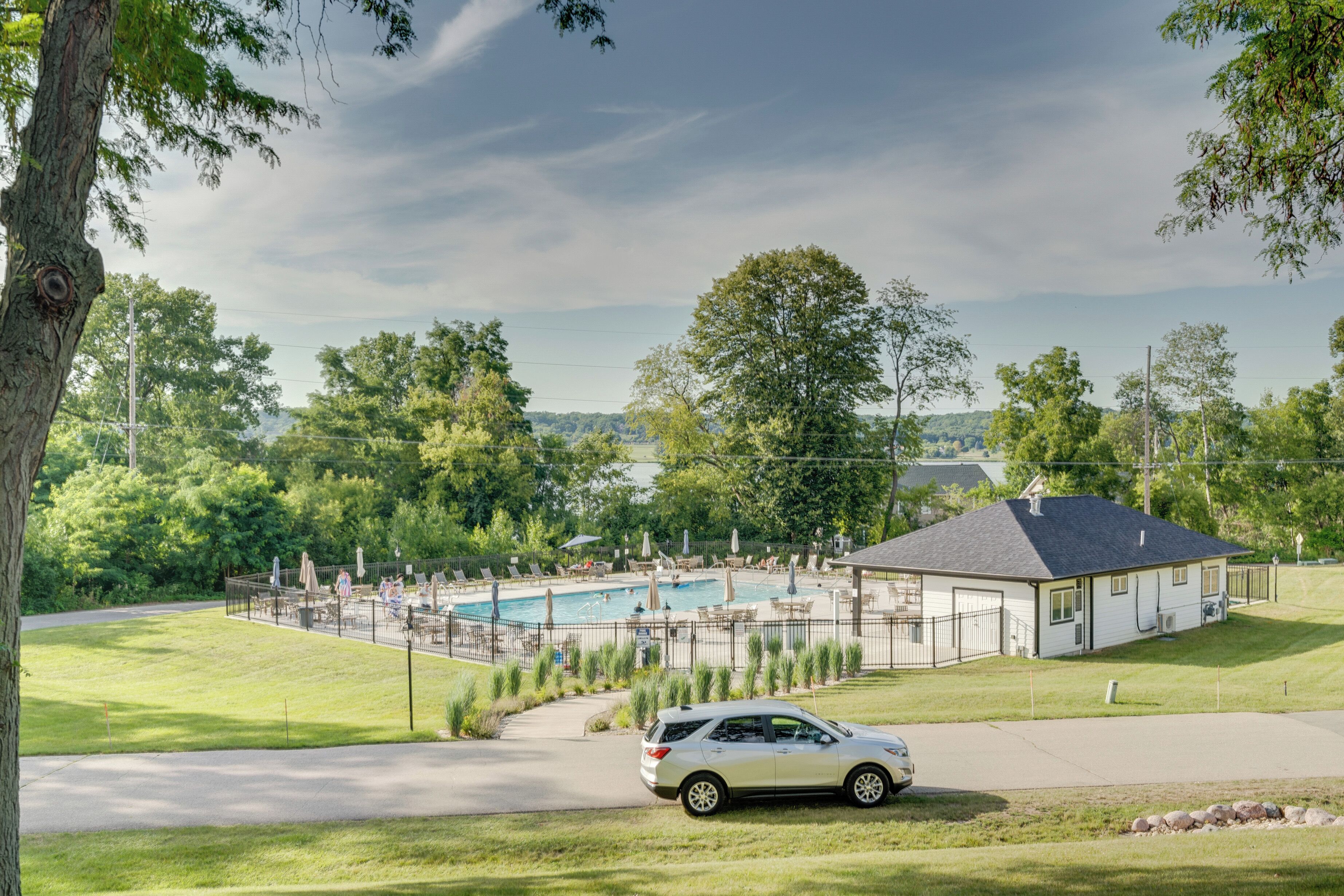 A residential area with a swimming pool, a house, and a parked car.