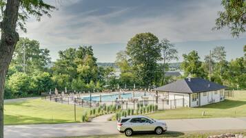 A residential area with a swimming pool, a house, and a parked car.