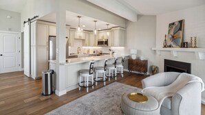 Cocina moderna con armarios blancos, electrodomésticos de acero inoxidable y una isla central con taburetes de bar.