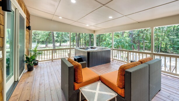A covered outdoor deck with wicker furniture, a hot tub, and potted plants. - Pottboro Vacation Rental w/ Private Hot Tub! (Pottsboro)
