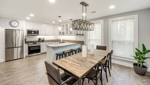 A modern kitchen with white cabinets, stainless steel appliances, and a wooden dining table with chairs. - Pottboro Vacation Rental w/ Private Hot Tub! (Pottsboro)