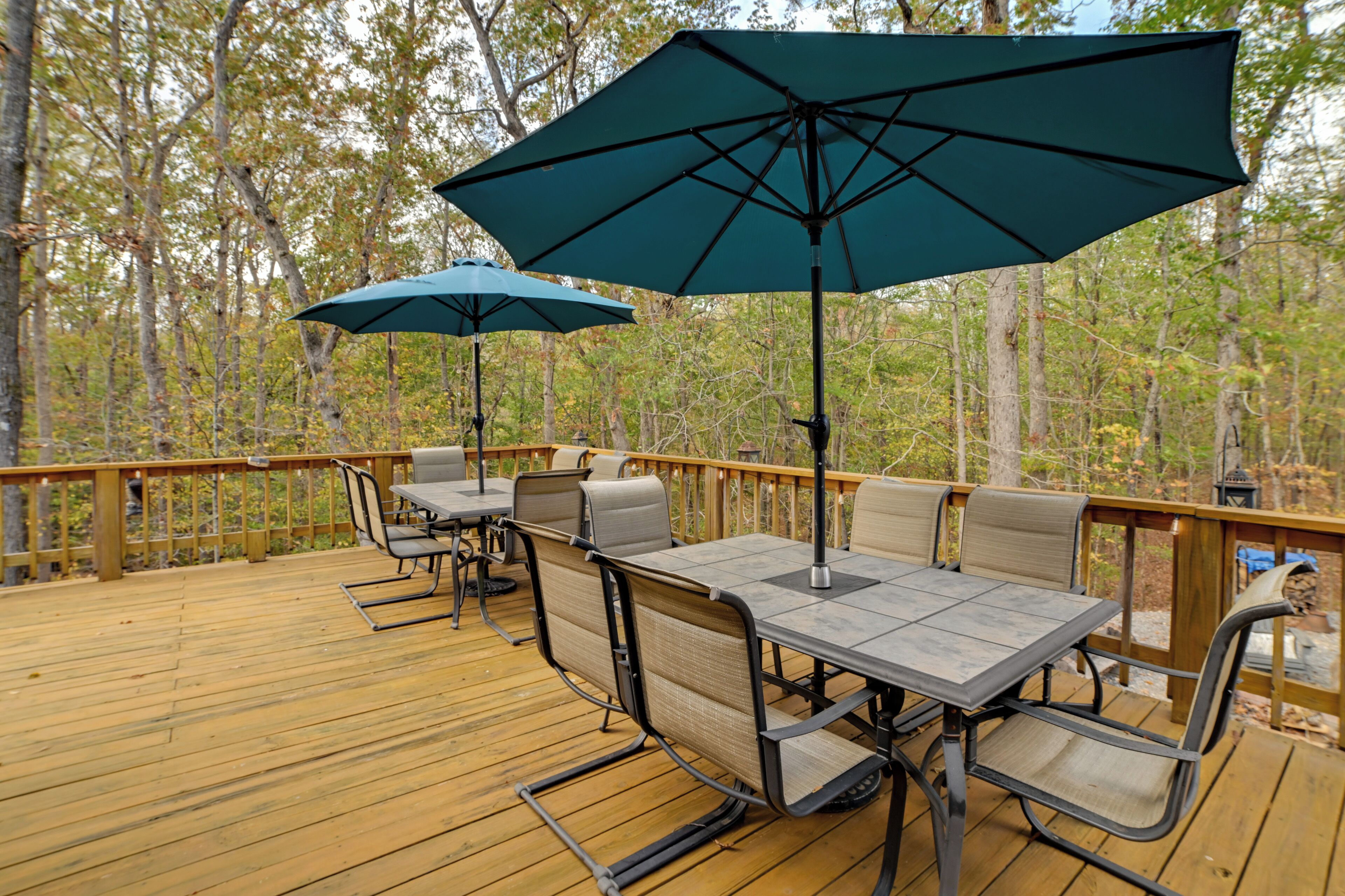 Une terrasse en bois aménagée avec du mobilier d’extérieur, notamment une table et des chaises, ainsi que deux parasols.