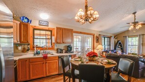 A spacious kitchen with wooden cabinets, a dining table, and a chandelier. - Cadiz Vacation Home w/ Deck: Walk to Lake Barkley (Cadiz)