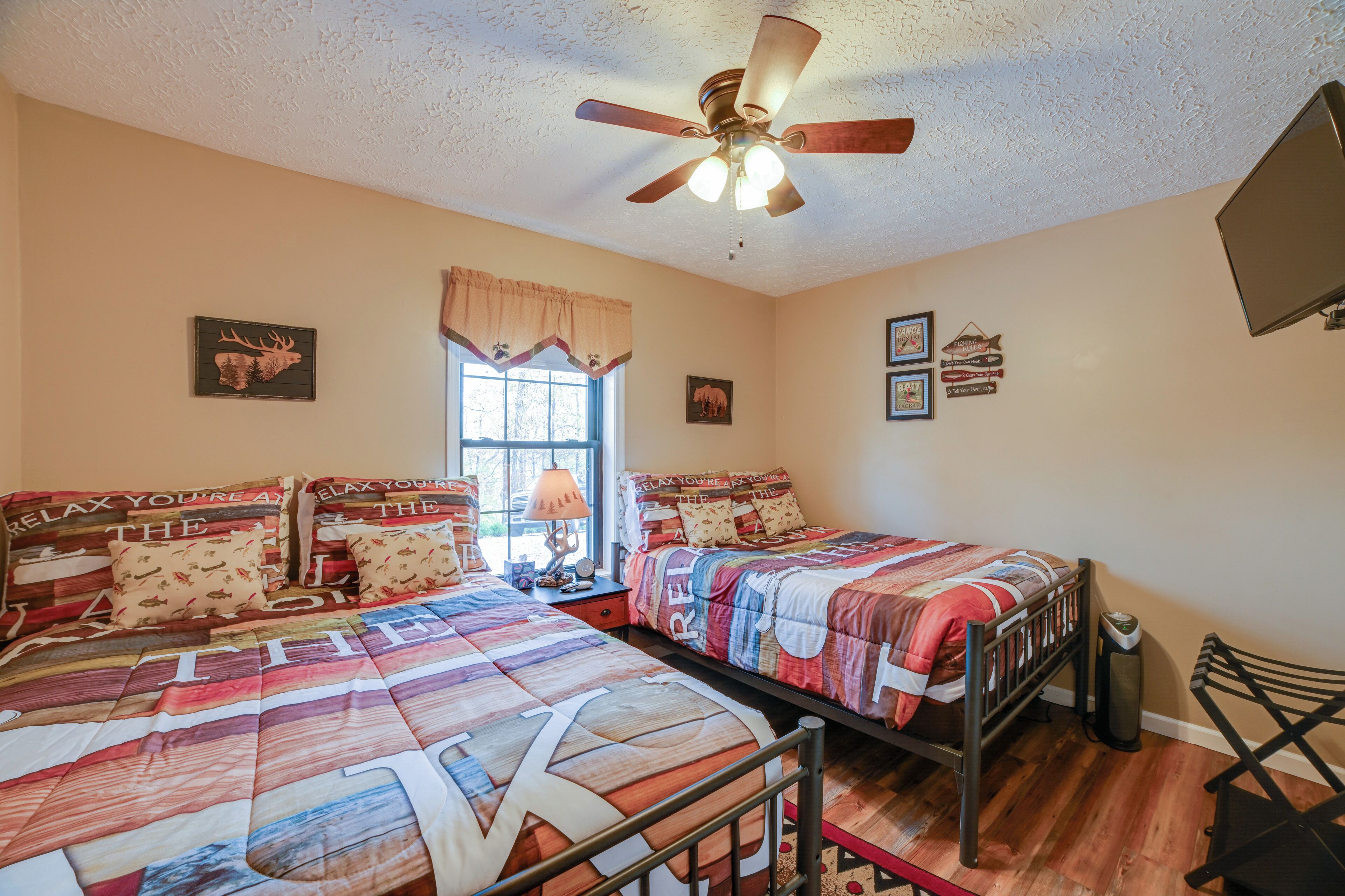 A bedroom with two beds, a ceiling fan, and a window with curtains.