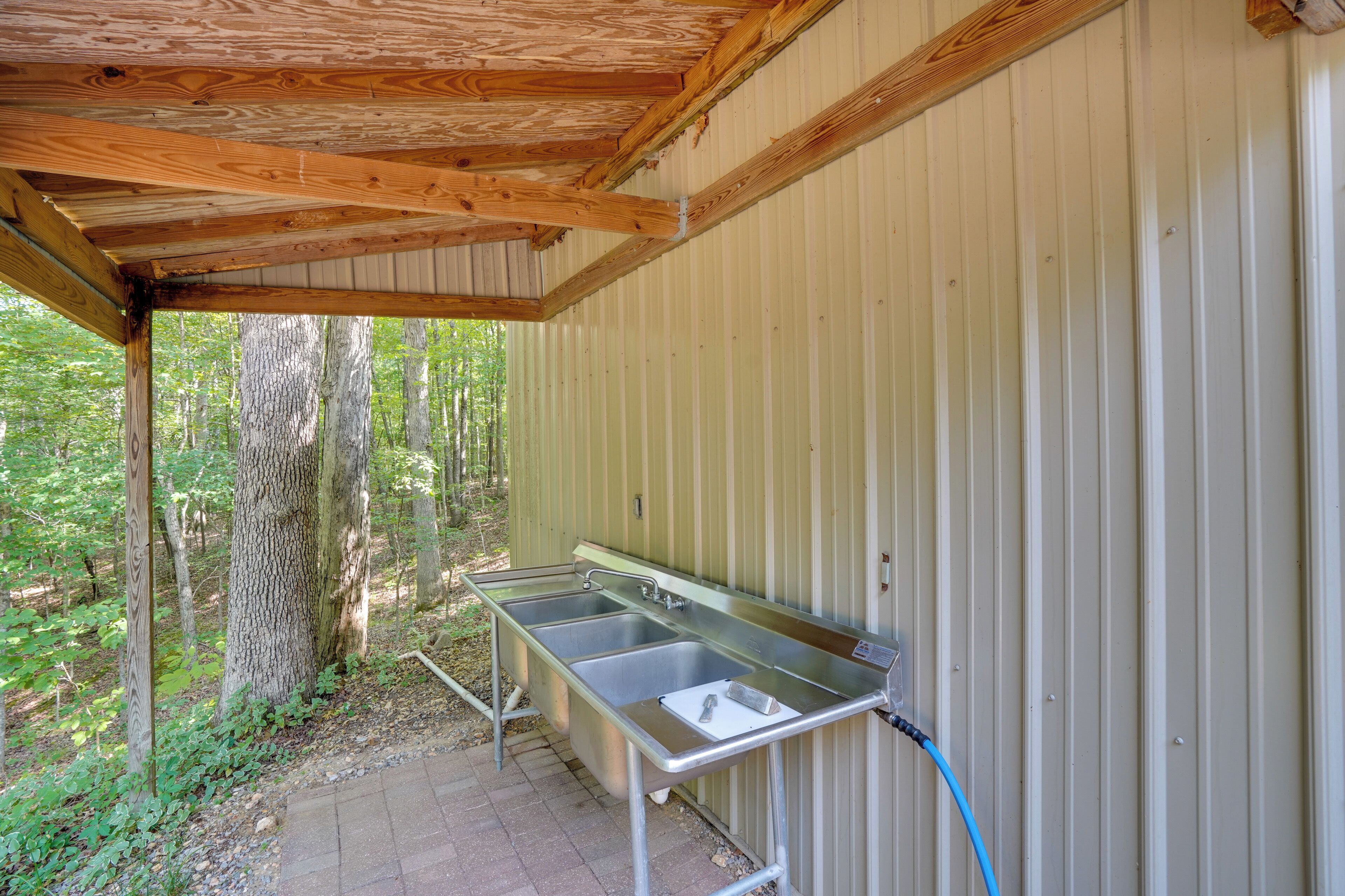 A metal outdoor kitchen with a wooden ceiling and a metal wall.