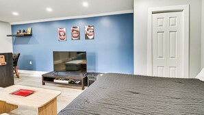 Een moderne slaapkamer met een groot bed, een televisie en een bijzettafeltje.