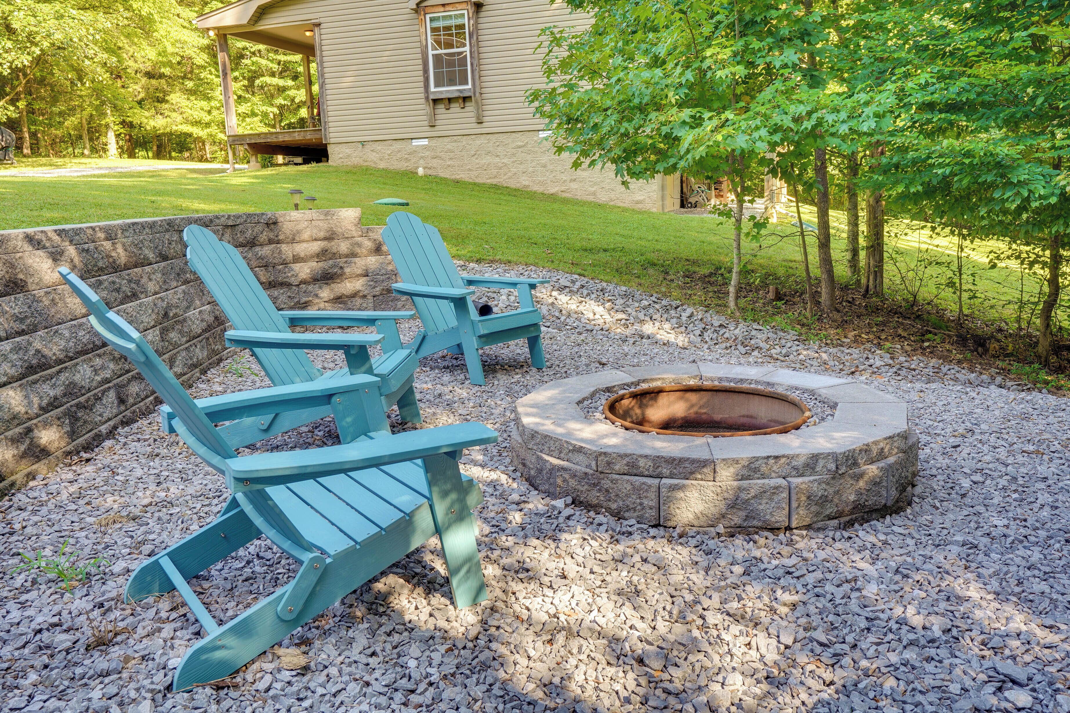 Un patio con sillas Adirondack y un hogar de piedra.