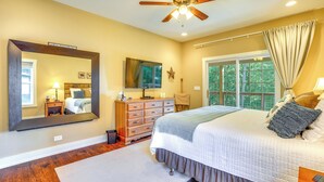 Une chambre à coucher avec un grand lit, un ventilateur de plafond, une commode, un miroir et une fenêtre avec des rideaux.