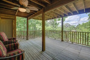 A wooden deck with a ceiling fan, a railing, and a view of a forest. - Lake Ouachita Vacation Rental w/ Community Pool (Mount Ida)