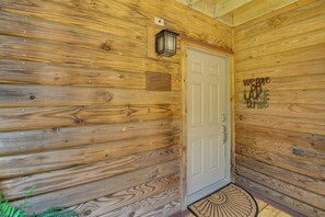 Una cabaña de madera con puerta blanca, una ventana pequeña y un felpudo.