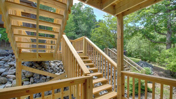 A wooden staircase leading to a deck with a view of a forested area. - Lake Ouachita Vacation Rental w/ Community Pool (Mount Ida)
