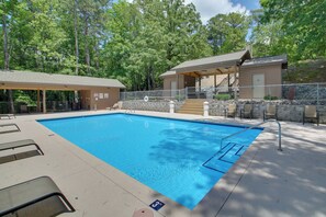 A swimming pool with lounge chairs, a covered seating area, and a building with a stone wall and a wooden deck. - Lake Ouachita Vacation Rental w/ Community Pool (Mount Ida)