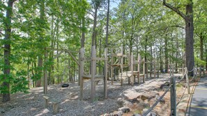 A forested area with wooden structures, including a bench and a playground. - Lake Ouachita Vacation Rental w/ Community Pool (Mount Ida)