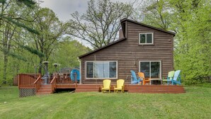 A wooden cabin with a deck, outdoor seating, and a large window. - Minnesota Cabin w/ Deck & Private Beach (Merrifield)