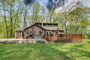 A two-story wooden house with a deck and a stone wall in front. - Minnesota Cabin w/ Deck & Private Beach (Merrifield)