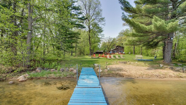 A wooden bridge leading to a cabin surrounded by trees. - Minnesota Cabin w/ Deck & Private Beach (Merrifield)