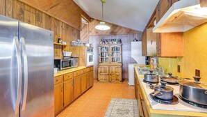 Une cuisine dotée de meubles en bois, d’un réfrigérateur en acier inoxydable, d’un four à micro-ondes et d’une cuisinière avec des casseroles.