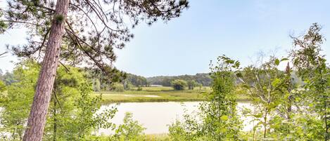 A natural landscape with a lake, dense greenery, and a clear sky.