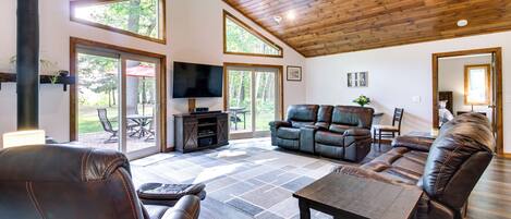 A spacious living room with a fireplace, leather sofas, and a television.
