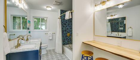 A bathroom with two sinks, a bathtub, and a large mirror.