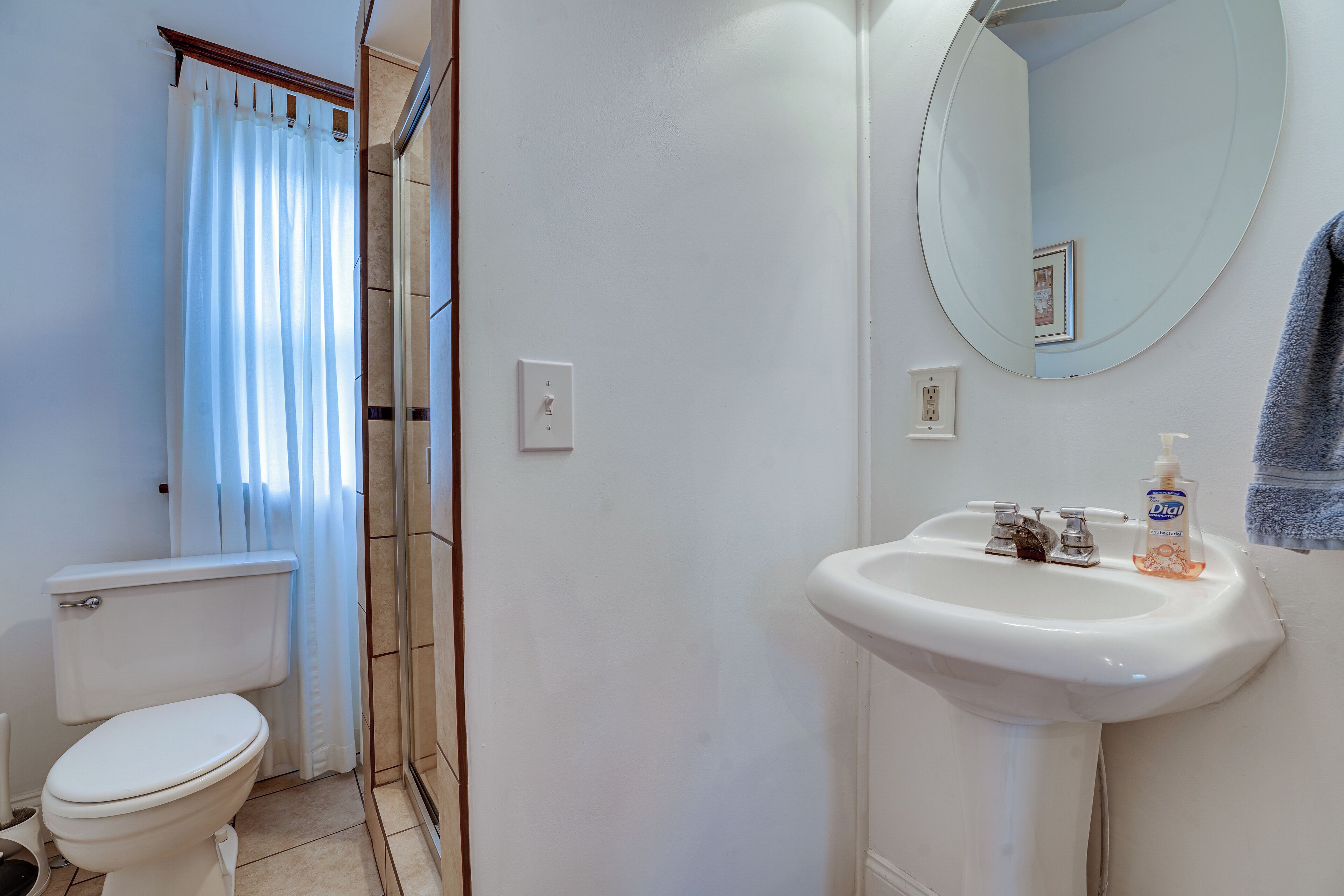 A bathroom with a toilet, a sink, a mirror, and a shower area.