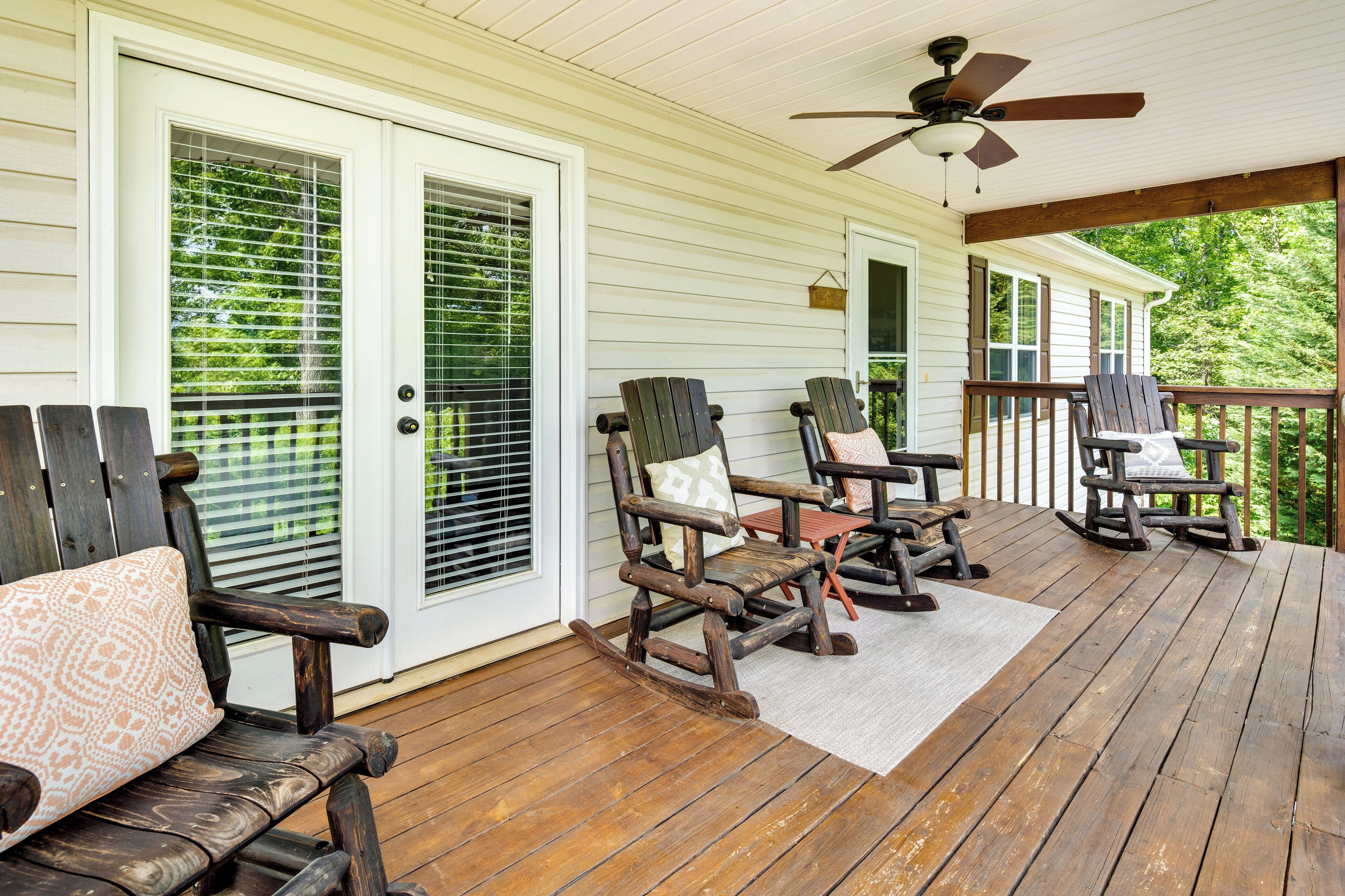 A covered porch with wooden rocking chairs and a ceiling fan.
