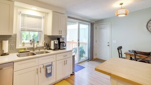A kitchen with a double sink, a coffee maker, and a dining area with a table and chairs. - Three Oaks Home w/ Guest House - 8 Mi to Beach! (Three Oaks)