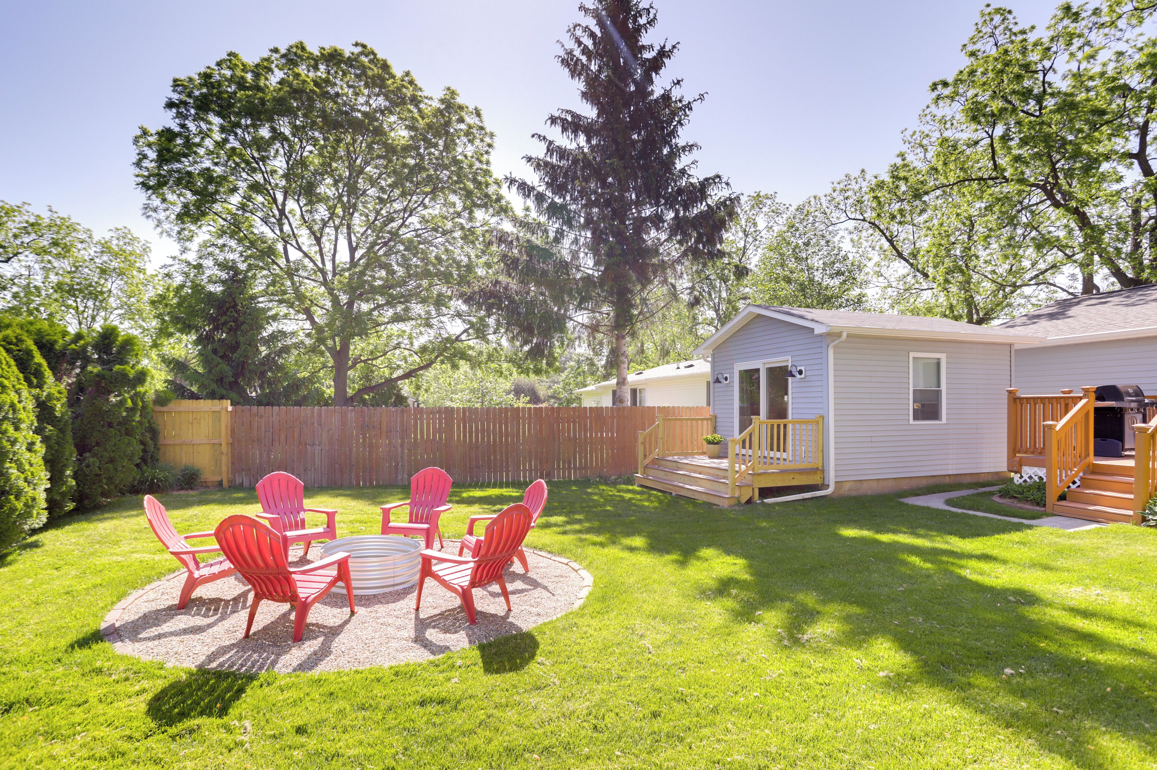 A backyard with a circular seating area, a wooden deck, and a small house.