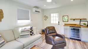 A living room with a sofa, a leather chair, a coffee table, a ceiling fan, and a kitchen area with a dishwasher. - Three Oaks Home w/ Guest House - 8 Mi to Beach! (Three Oaks)